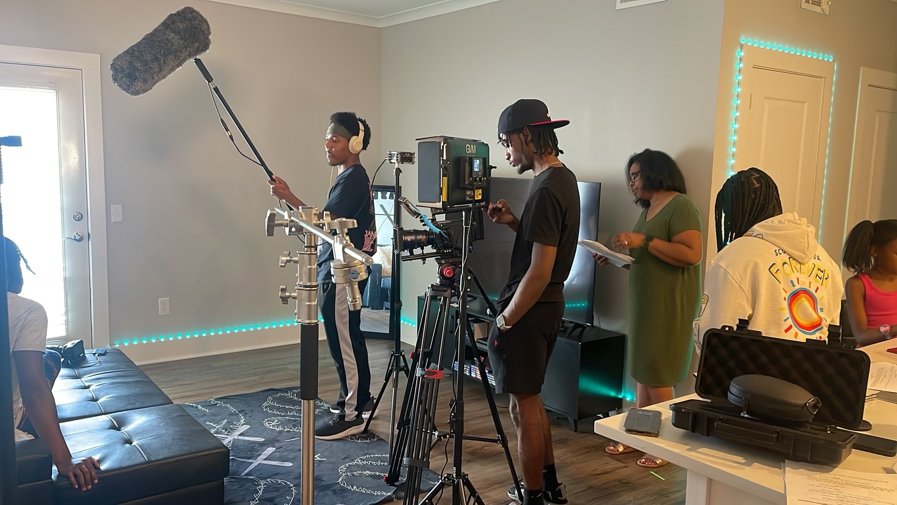 Sound operator raises a boom microphone over a living room scene.