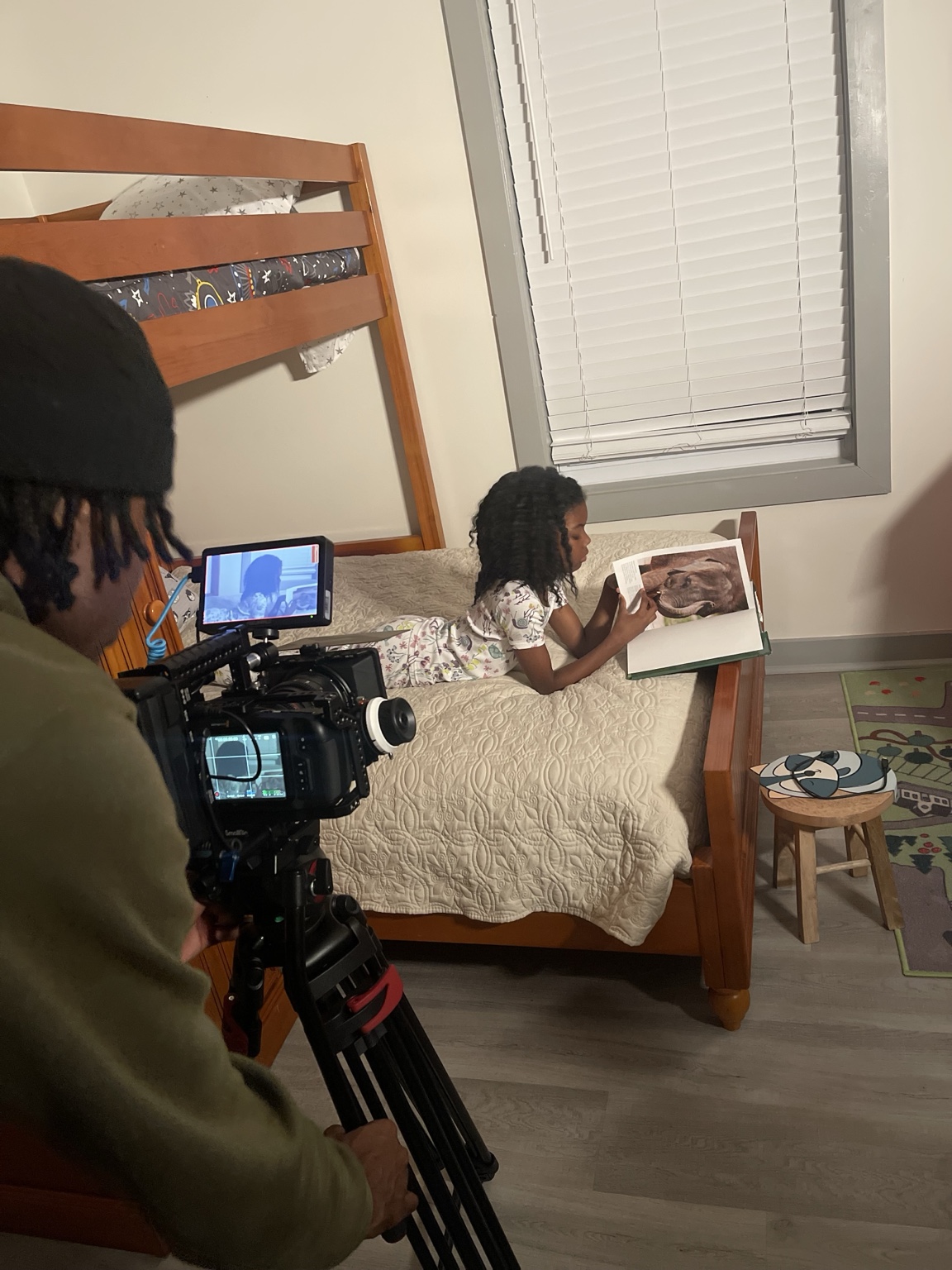 Camera crew films a child reading on a bed.